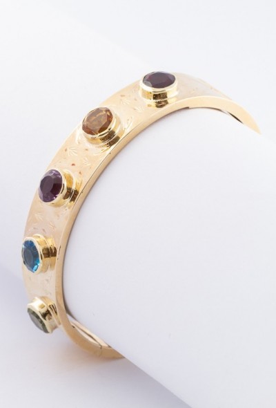 Gouden bangle met diverse edelstenen.